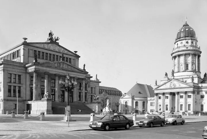 Concert hall and Franz. Cathedral behind 3 standing cars