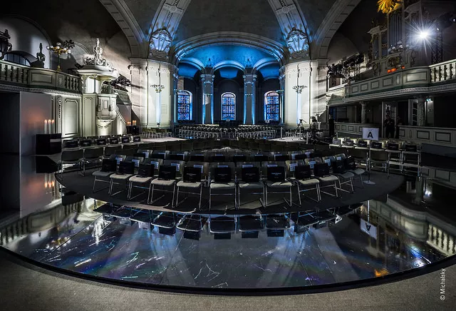 Large hall with black chairs, blue mood lighting and black marble floor
