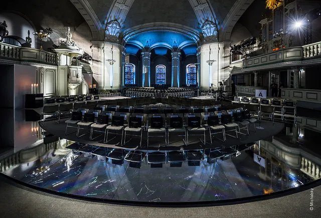 Großer Saal mit schwarzem Stühlen, blauem Stimmungslicht und schwarzem Marmorboden